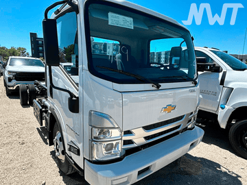 White Chevrolet truck in a parking lot with a blue sky and other vehicles in the background.