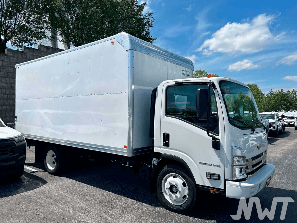 White delivery truck in a parking lot with trees and blue sky in the background