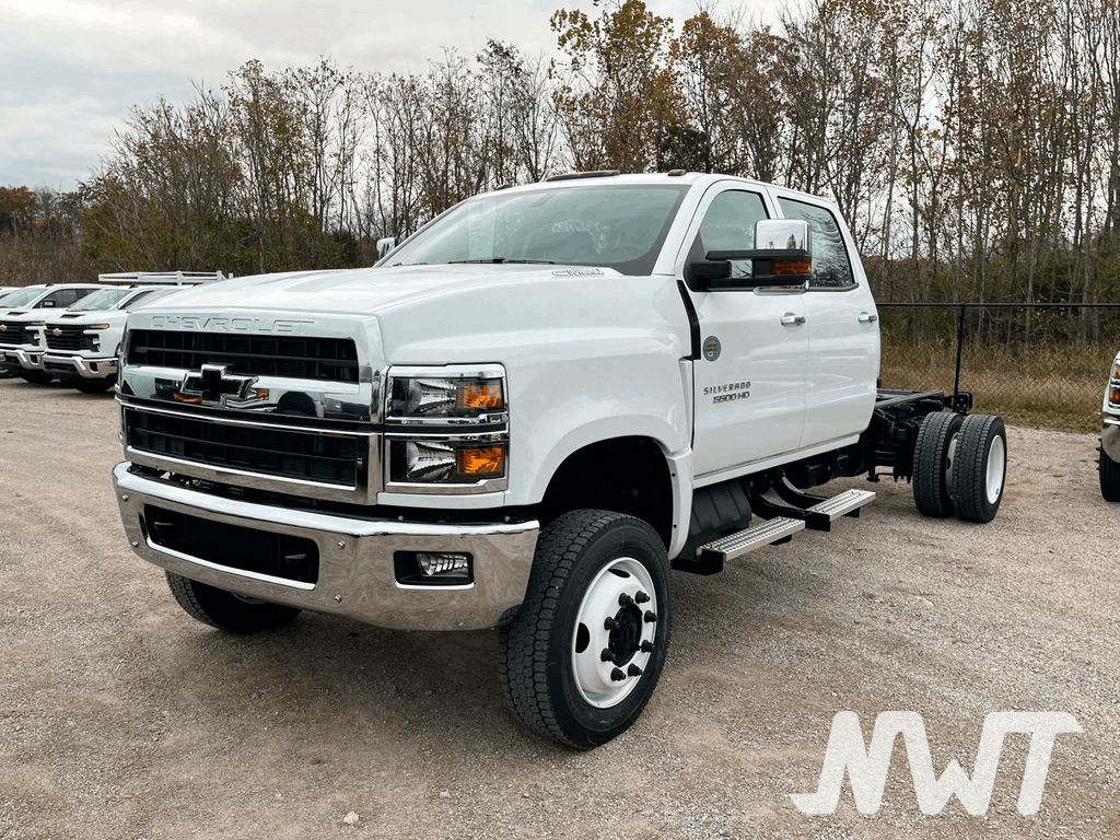 White Chevrolet truck on a gravel lot with trees in the background