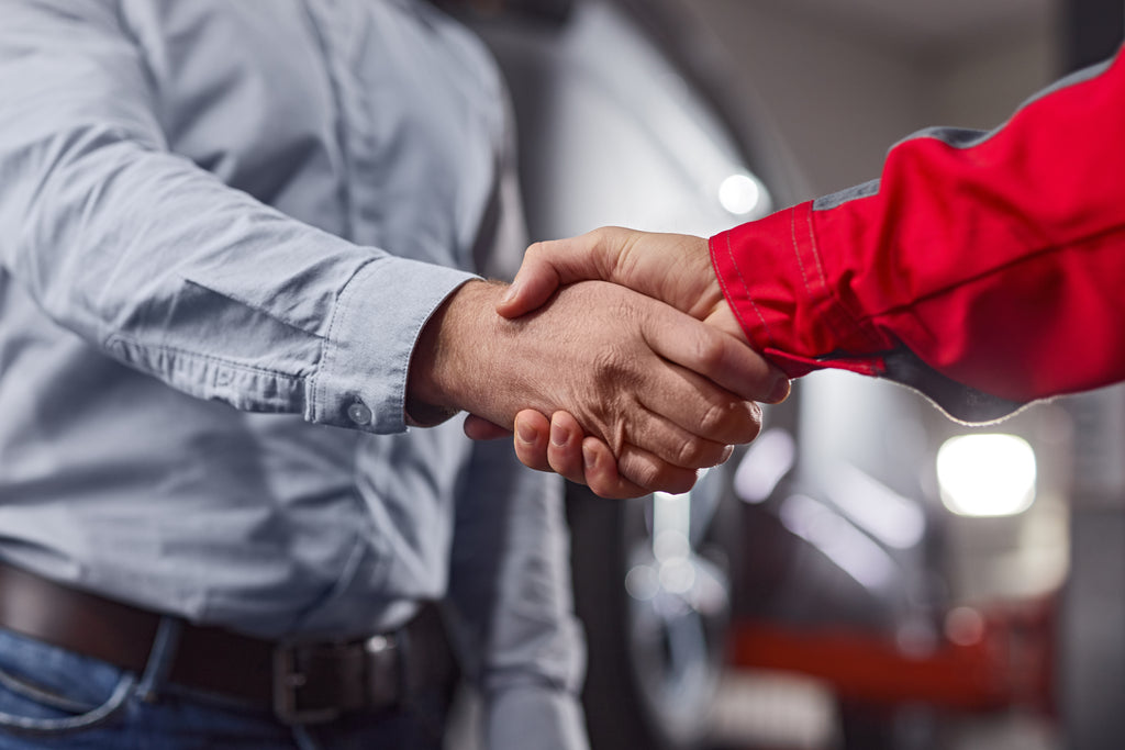 two people, one with red shirt and the other one grey, shaking hands